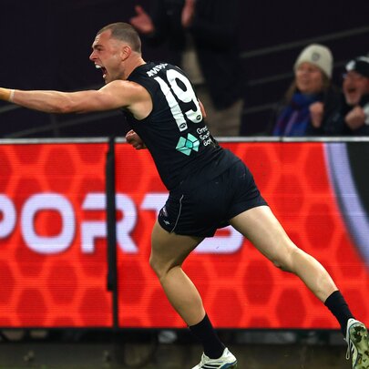 A Carlton Blues AFL player pointing in celebration during a game.