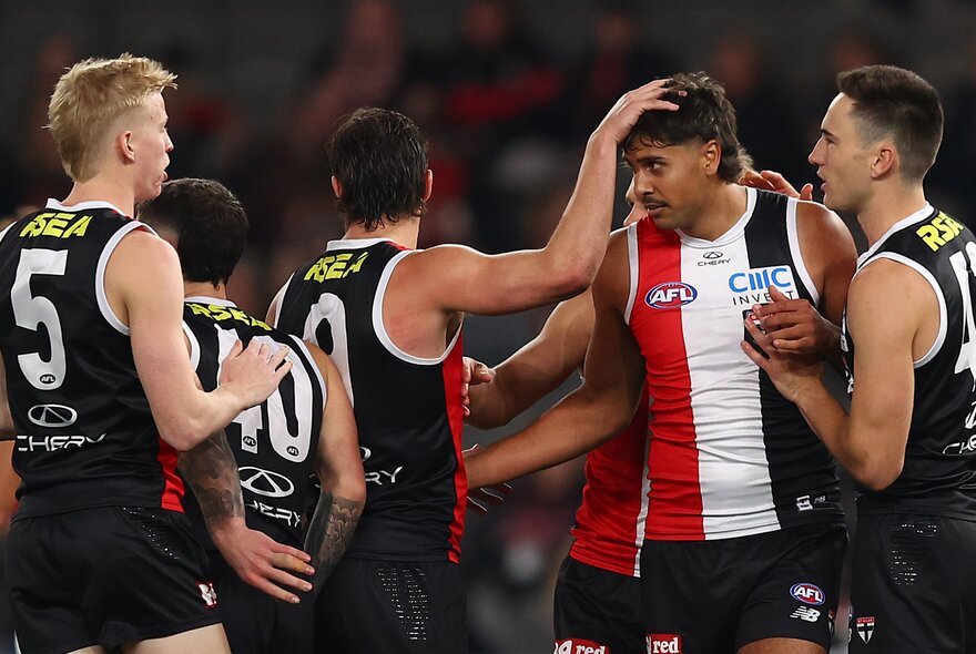 St Kilda players congratulate a team mate by patting him on the head. 