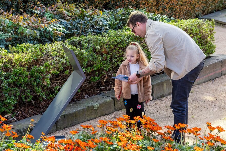 Adult and child looking at a sculpture in a garden.