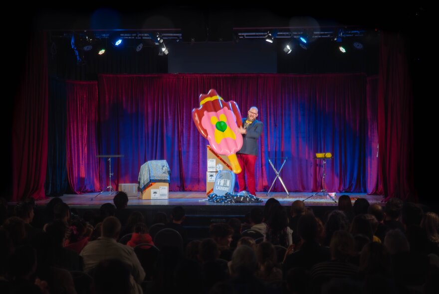 Magician performing on stage with colourful props.
