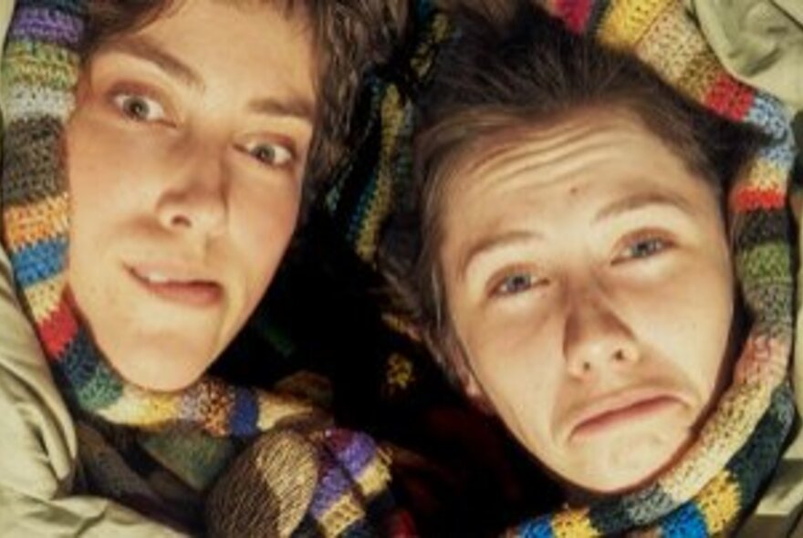 Two people with faces grimaching, wearing striped scarves.