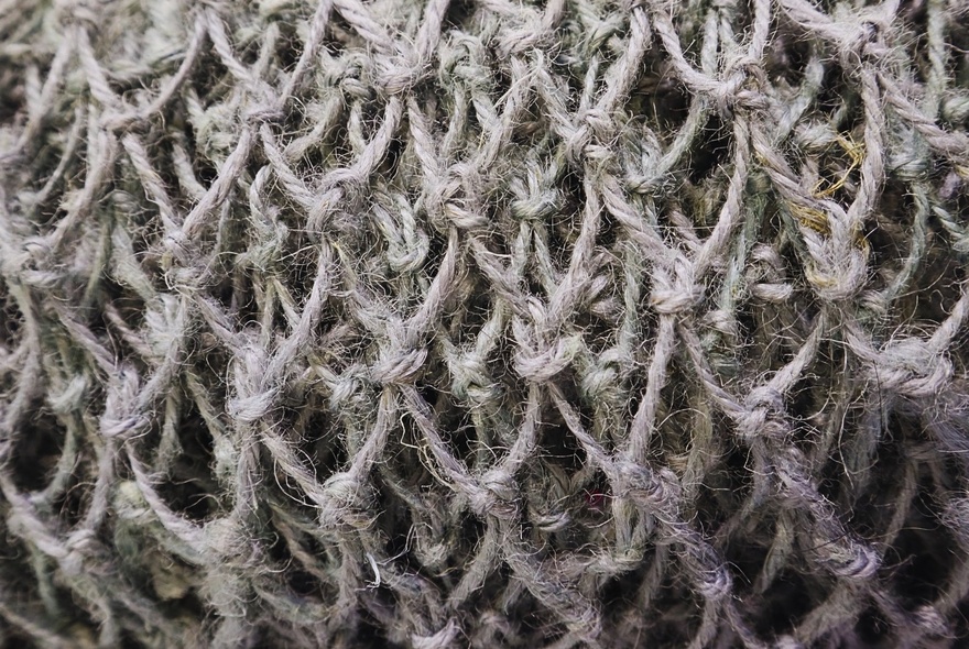 The dense weave of a piece of woven artwork, seen from close up.