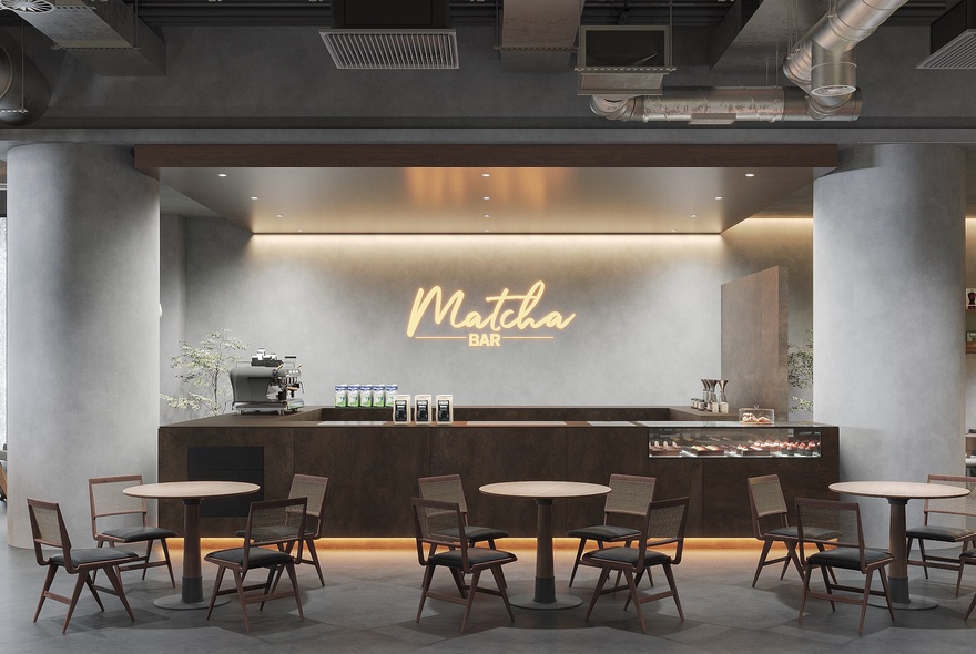 Interior of a stylish restaurant, with a central sleek bar, and small round tables and chairs in front of this space, and the words 'Matcha Bar' written on the back wall.