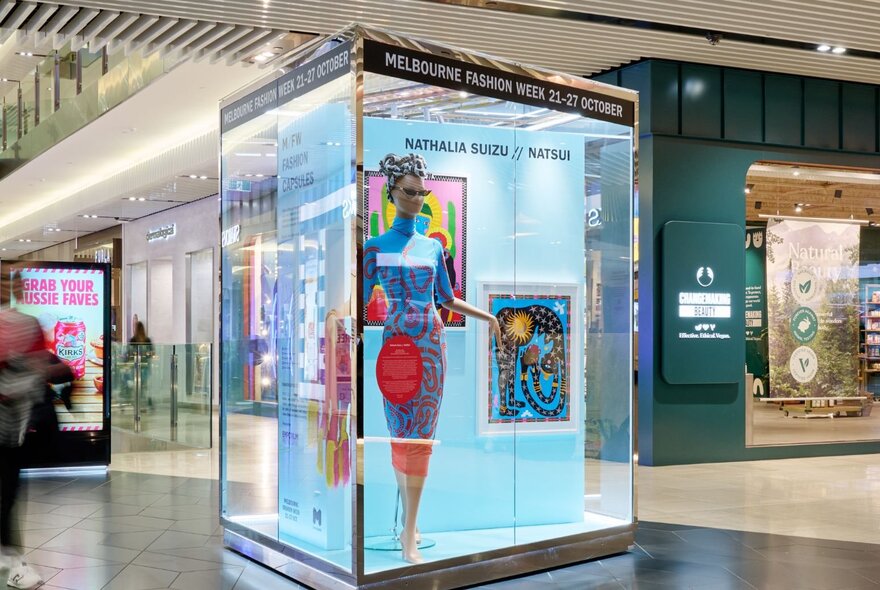 A fashion exhibit featuring a mannequin in a glass box. 