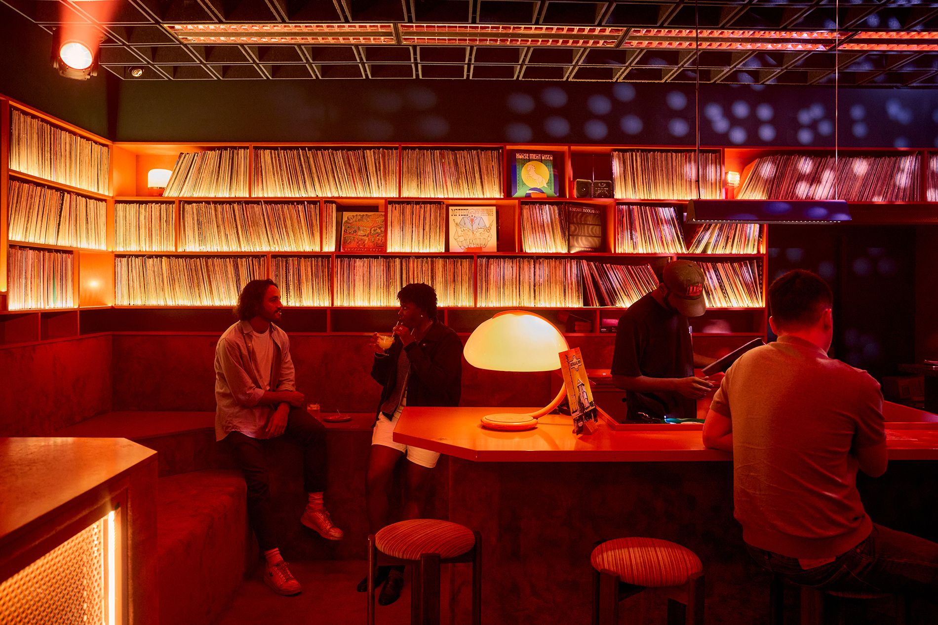 People sitting in a warmly lit bar with records lining the walls.