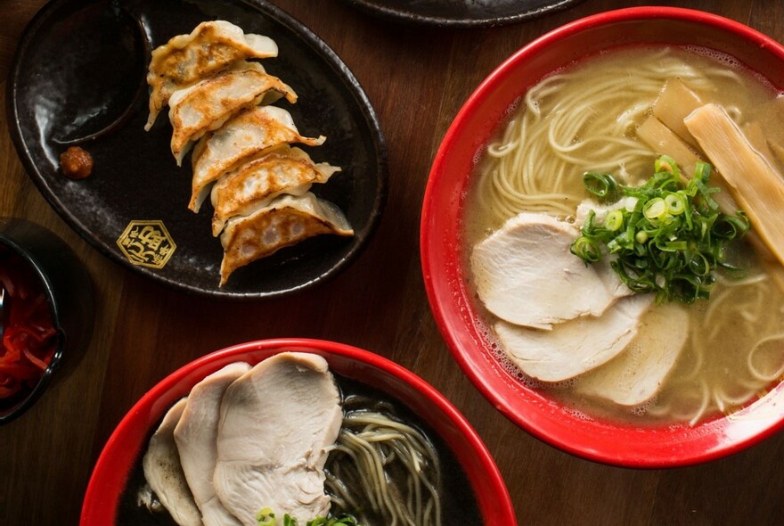 Bowls of ramen noodles and plate of fried dumplings.