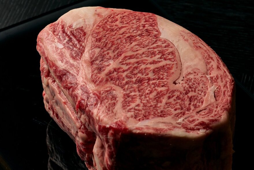 A piece of premium Wagyu fillet with marbled fat, resting on a black plate.