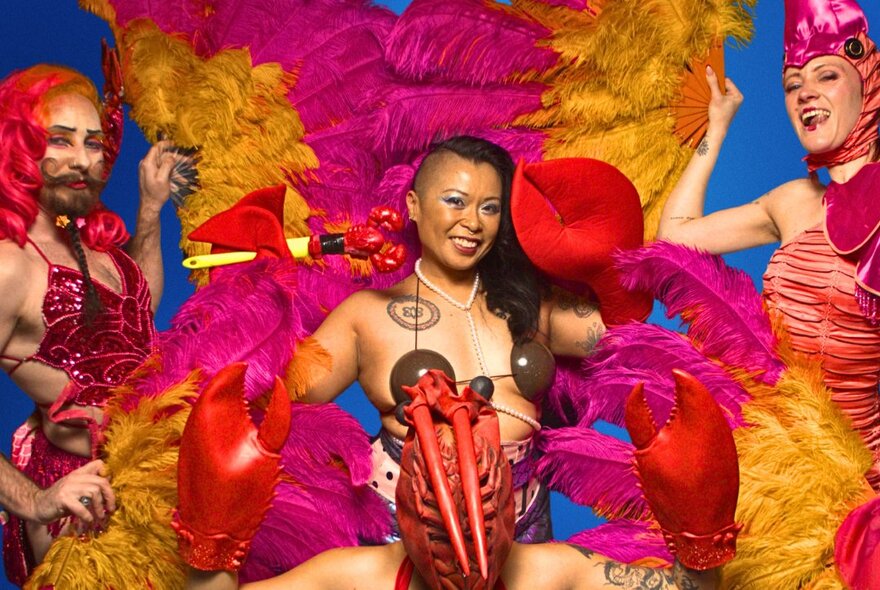 Four cabaret performers surrounded by pink and yellow feather fans.