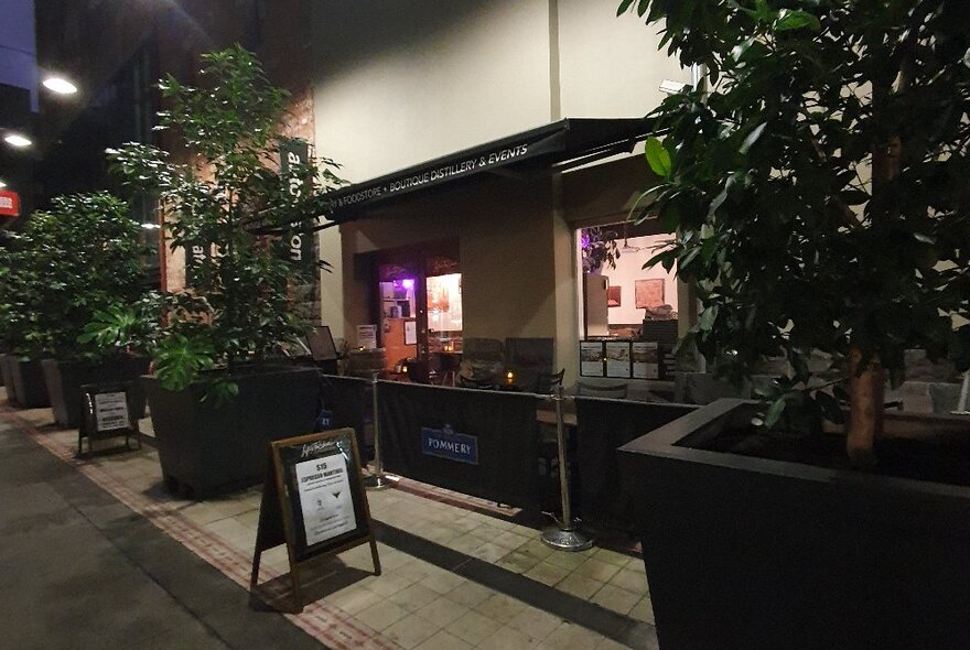 The exterior building of Life's Too Short Bar with large potted plants on the footpath.