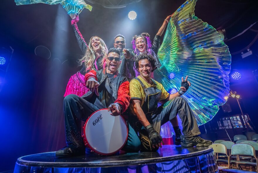 Five children's circus performers on stage in colourful costumes.
