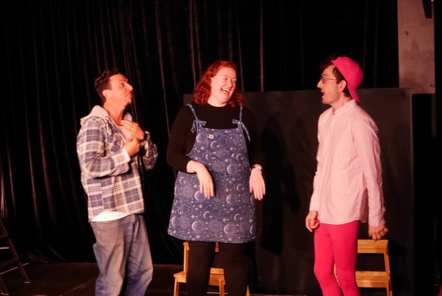 Three actors on stage performing an improvised theatre routine.