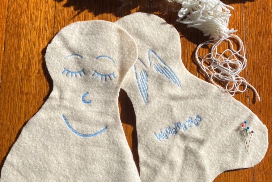Cut out pieces of flat white wool, with thread,  and stuffing, ready to be sewn into plush soft angels.