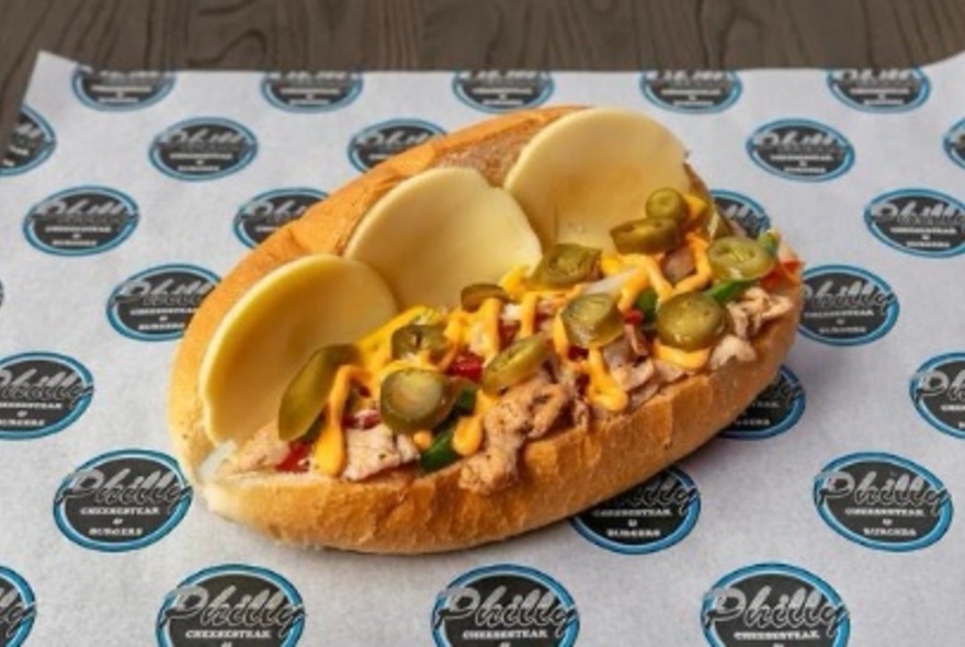 An open Philly cheesesteak roll showing jalapeños meat and cheese. 