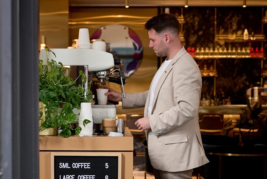 A barista in a beige blazer preparing coffee in a casual environment.