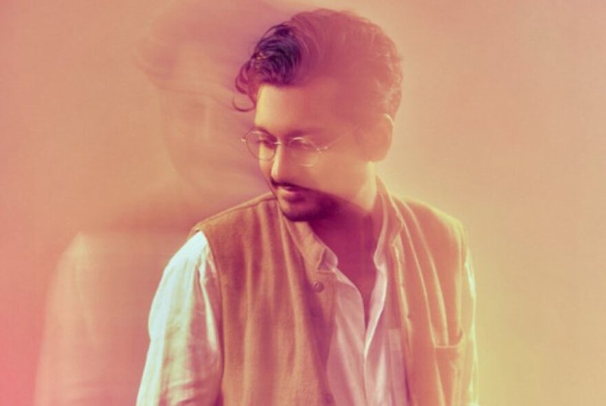 Comedian Ahir Shah in a blurred motion, overlayed image in warm orange tones. 