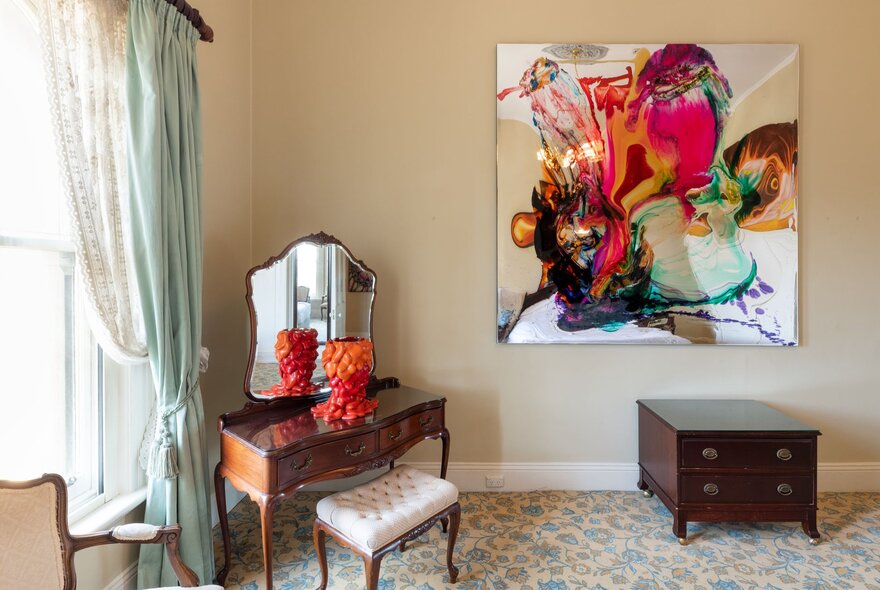 A room at Hotel Windsor decorated with a large abstract painting hanging on the wall and a small sculpture on a dressing table.