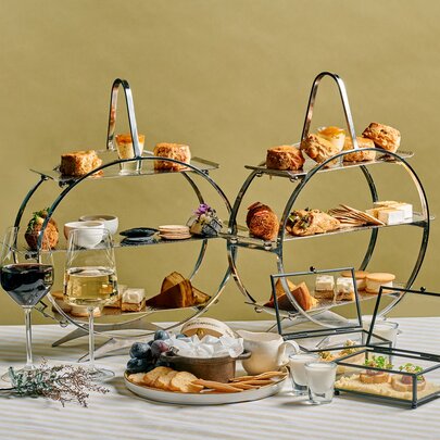 Two three-tiered cake stands displaying sweet and savoury cheese treats on a white table.