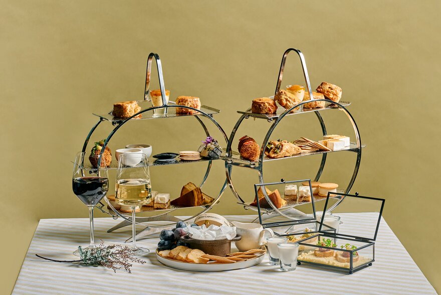 Two three-tiered cake stands displaying sweet and savoury cheese treats on a white table.