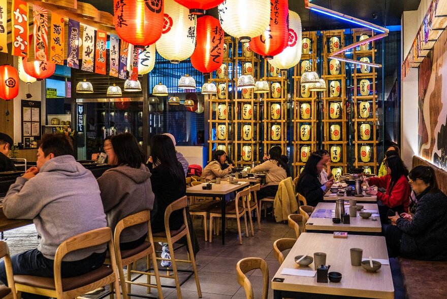 A group of people are eating in a Japanese restaurant. 