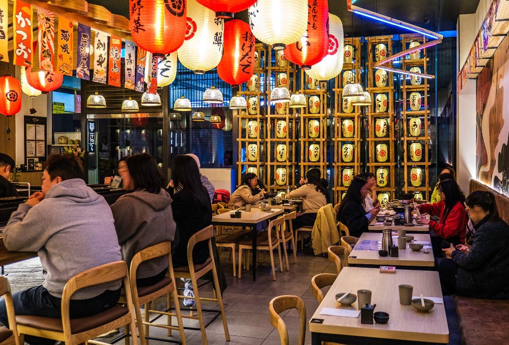 A group of people are eating in a Japanese restaurant. 
