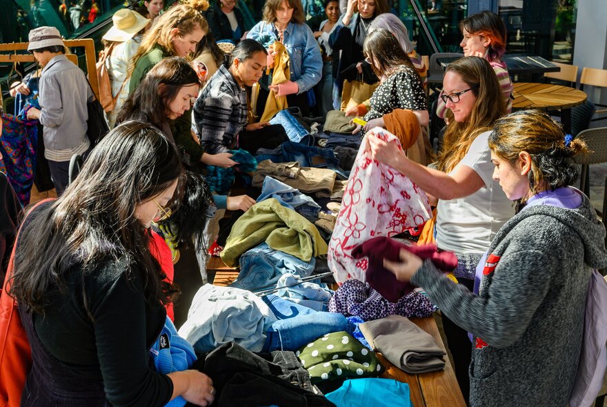 People looking at bolts of fabric in a market space.
