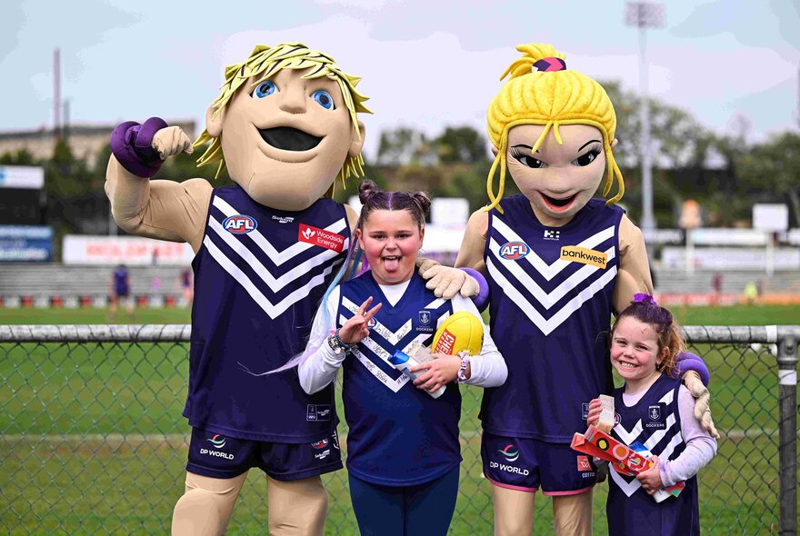 Fremantle AFLW mascots with two young supportes at the footy. 