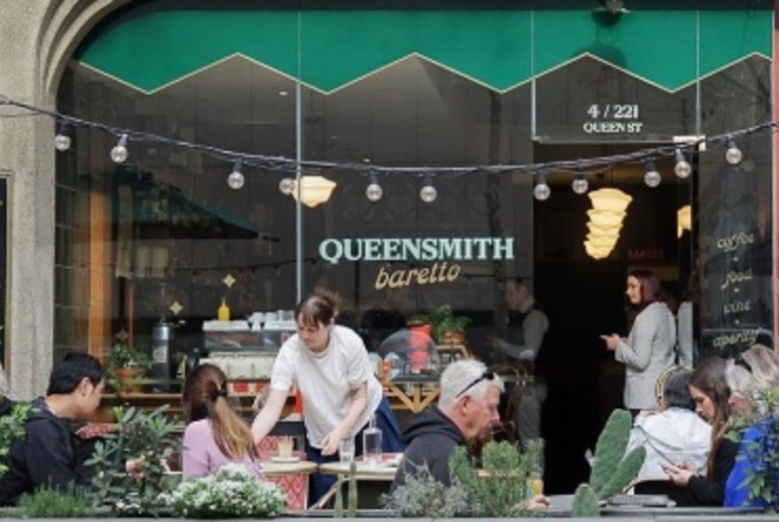 Outside tables at Queensmith Baretto with patrons seated and a waiter attending. 