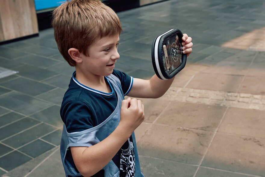 A child interacting with a digital device in an open square.