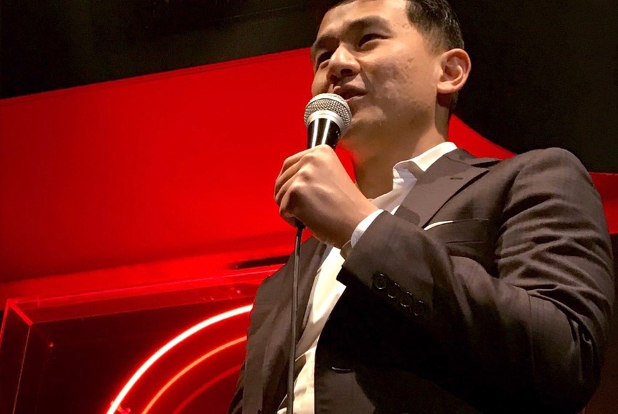 Close up of stand-up comedian Ronny Chieng holding a microphone.