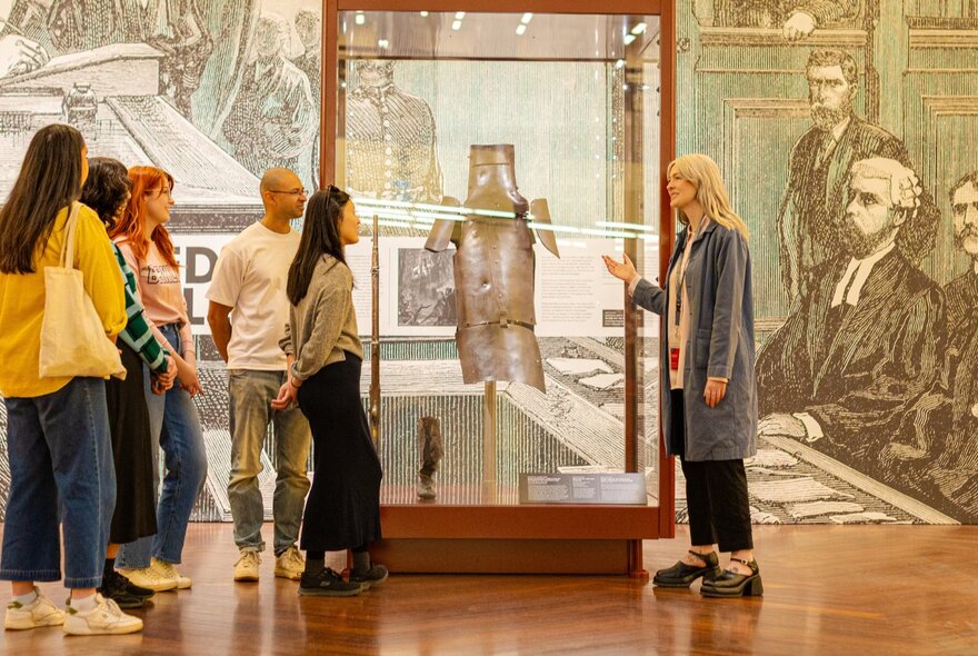 A small tour group looking at the Ned Kelly armour in a glass case.