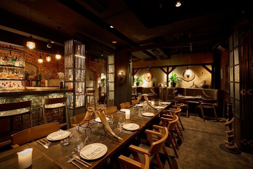 The darkened interior of a Viking-style restaurant with a large banquet table set with viking horn drink vessels.