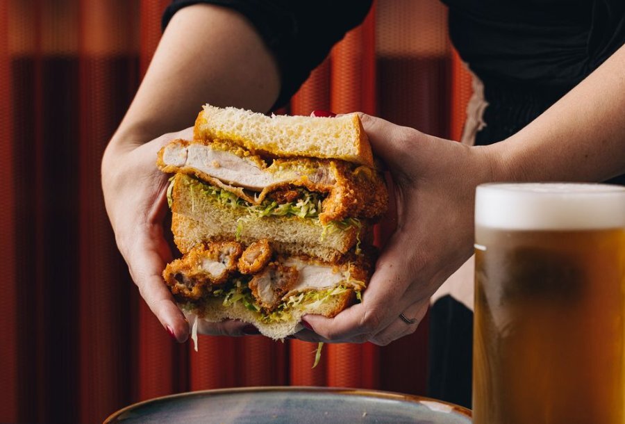 A person holding a fried chicken sandwich with two hands.