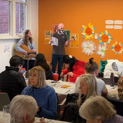 People attending a workshop in a small classroom setting with orange walls. 