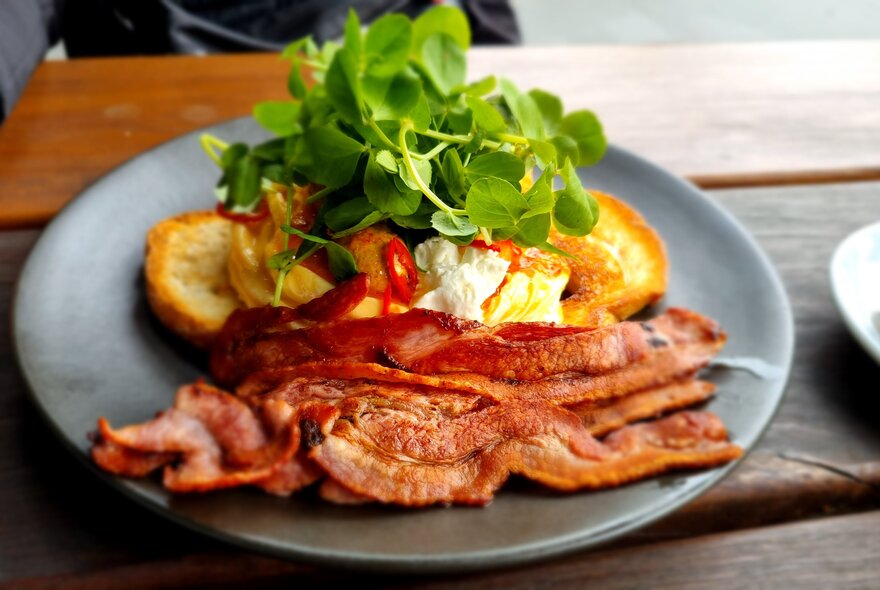 A plate of crispy bacon, eggs and watercress. 