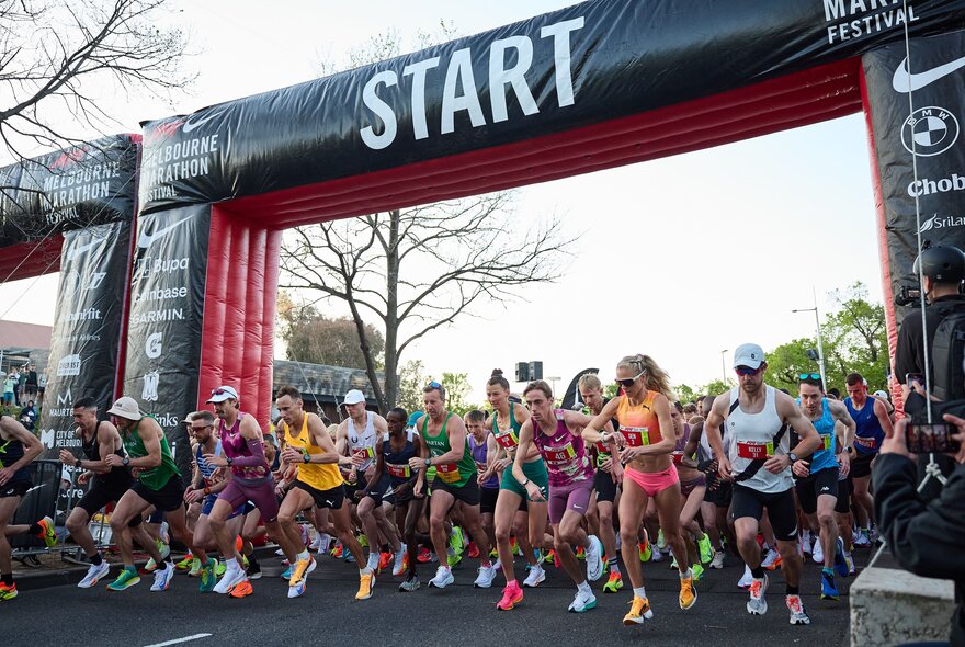 A large group of runners at the start line of a marathon race.