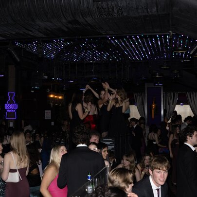 People at an evening black-tie event with twinkling lights in the background.