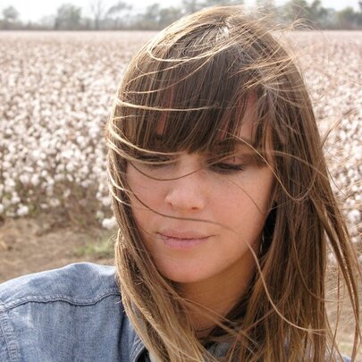Singer-songwriter Cat Power, wearing denim, standing in front of cotton fields.