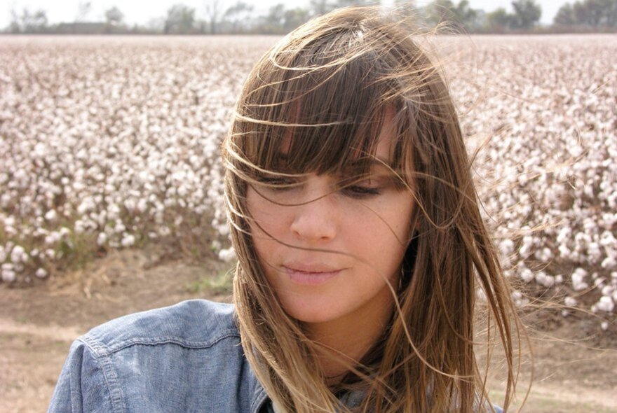 Singer-songwriter Cat Power, wearing denim, standing in front of cotton fields.