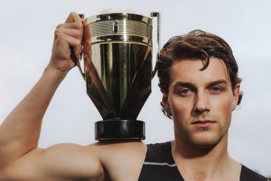 Man with coiffed hair and makeup holding gold sporting cup.