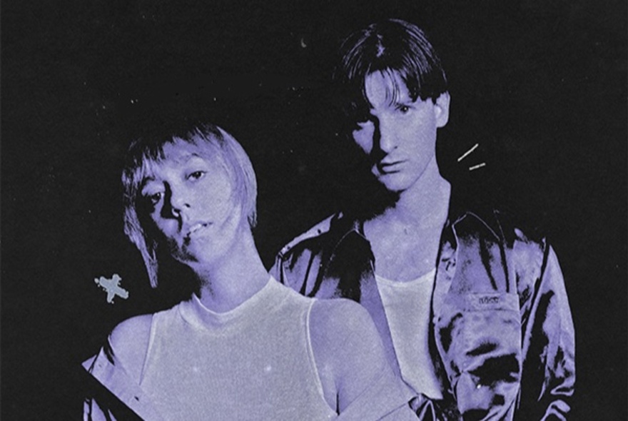 Purple-hued dark-toned image of musical duo wearing shiny top and jacket.