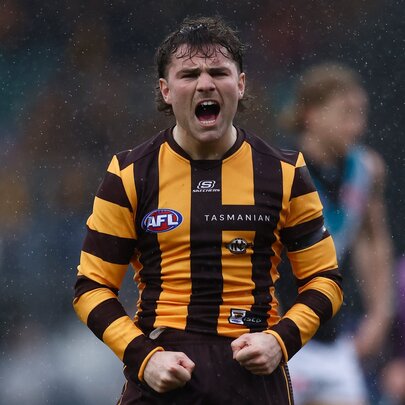 Hawthorn AFL football player standing during a match with fists pumped, yelling.