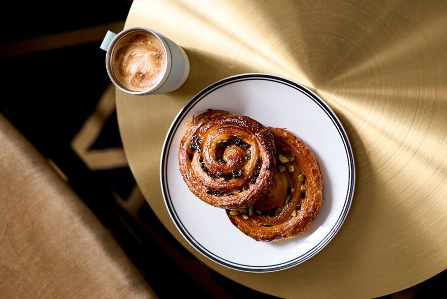 Looing directly down on two pain au raisin and a cup of coffee. 