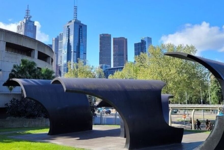 Architectural wave-like sculpture in a public place with the Melbourne skyline visible in the background. 