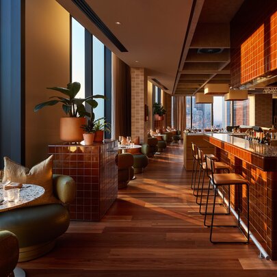 A view of the empty Langlands restaurant with the sun rising over the city seen through the windows.