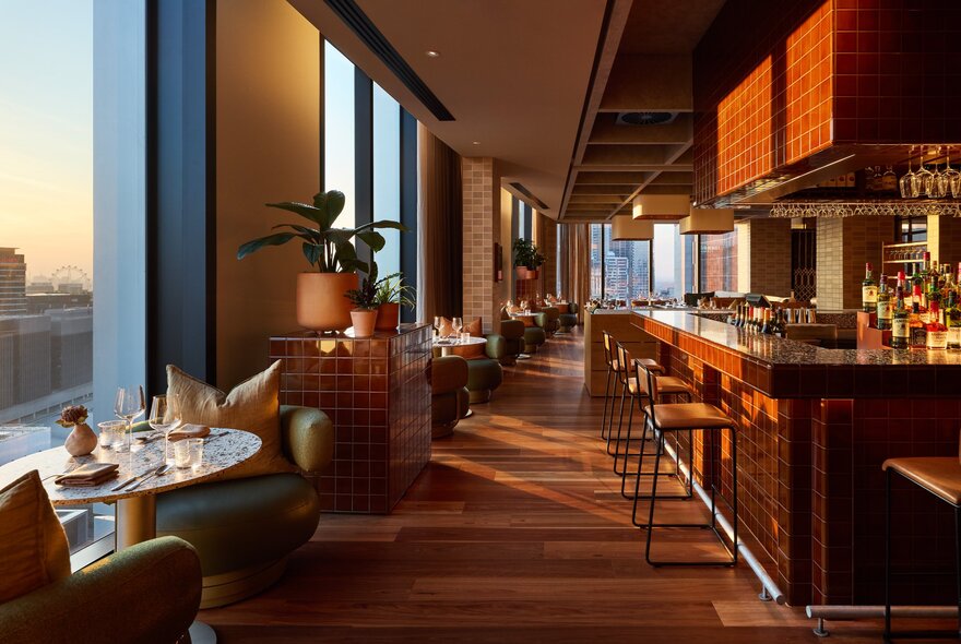 A view of the empty Langlands restaurant with the sun rising over the city seen through the windows.