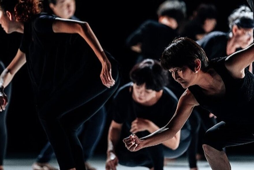 Older people wearing black shirts, dancing in a group.