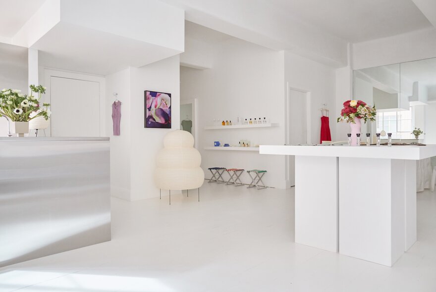 A sparse white shop interior with a centre counter, white floors and walls.