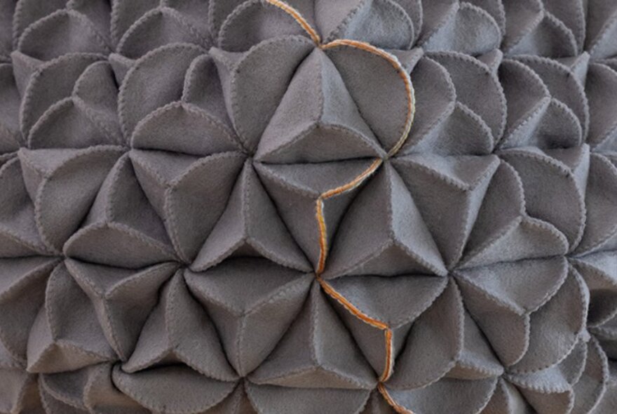 A woven sculpture made from a felted fabric, in the form of a tetrahedron.