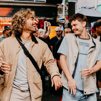 Two individuals enjoying themselves dancing at a crowded outdoor bar.