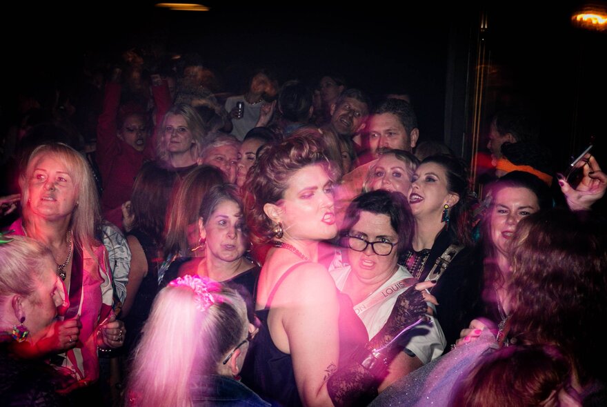 People on a crowded dance-floor looking serious.